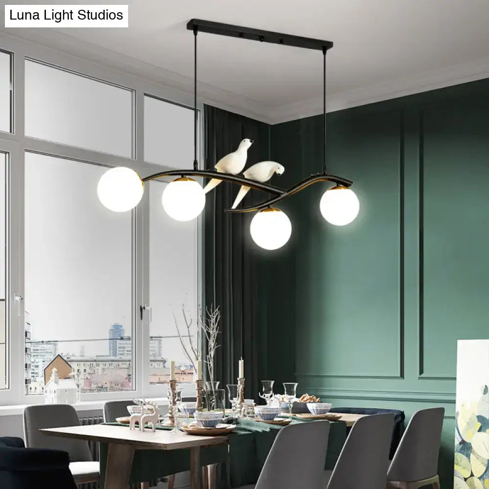 Modern black metal chandelier featuring four white glass globes and two white birds on a lamp tree branch design