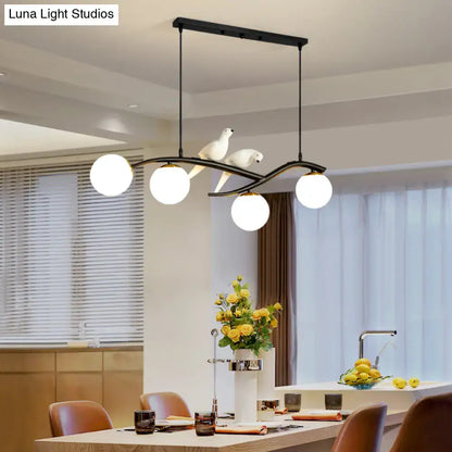 Modern black metal island lamp tree with three white glass bulbs and sculpted white doves on lamp tree branch