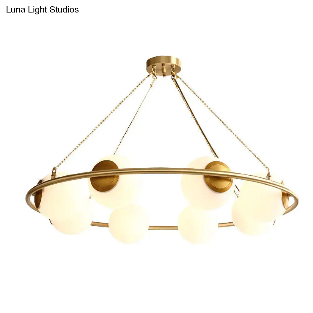 Gold-toned DecorBites™ postmodern metal chandelier with brass finish circular frame and frosted glass globe shades suspended by chains