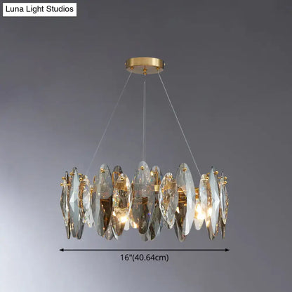 A modern gold chandelier with clear crystal discs complements the postmodern smoke grey glass leaf suspension lamp design