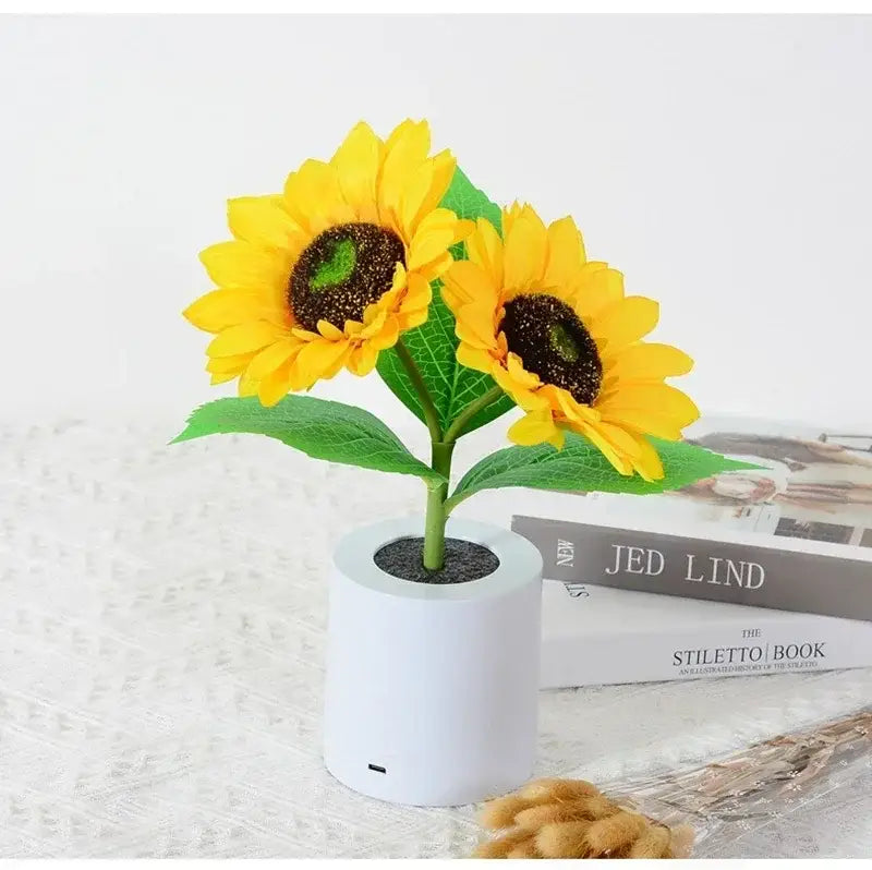 White cylindrical rechargeable speaker with two yellow sunflower led night lights and green leaves for bedroom use