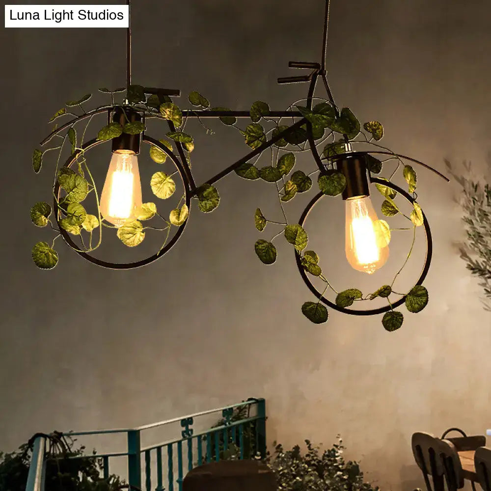 Black metal bicycle restaurant ceiling light with two glowing bulbs and green plant decor wrapping the frame