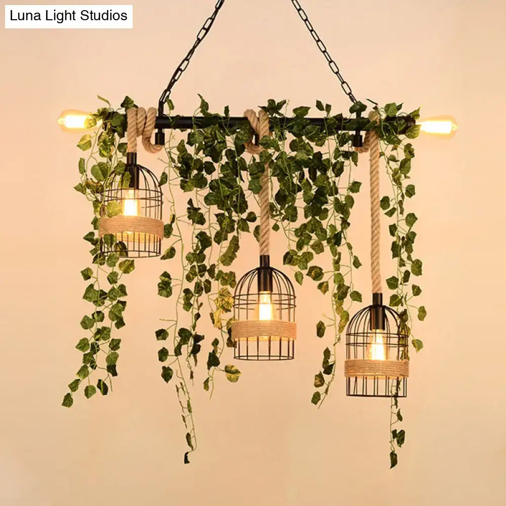 Industrial-style decorbites™ retro metal island light with three black birdcage lamps, rope accents, and hanging green ivy