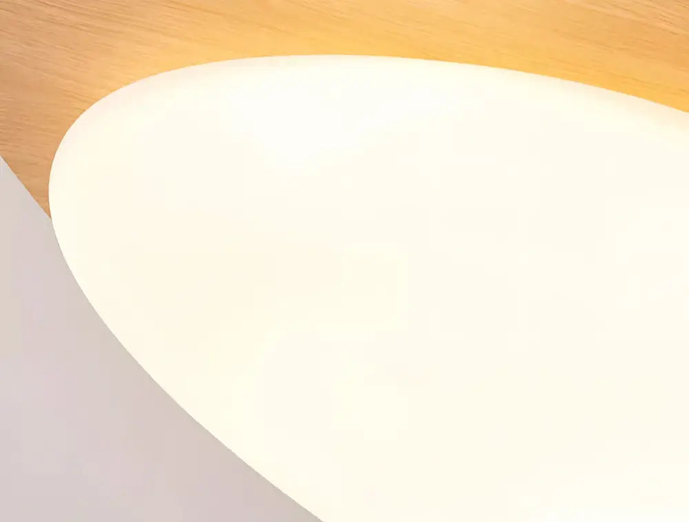 A sleek white oval lampshade with a matte finish resting on a warm walnut color wooden surface for living room ceiling light