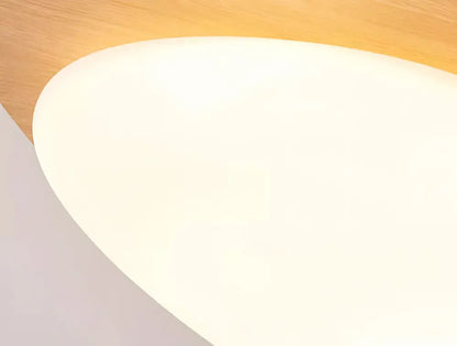 A sleek white oval lampshade with a matte finish resting on a warm walnut color wooden surface for living room ceiling light