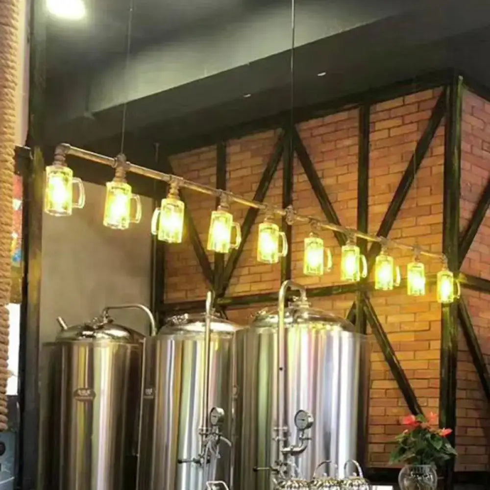 A row of illuminated clear glass beer mugs hanging from a bronze rustic bar ceiling pendant light fixture