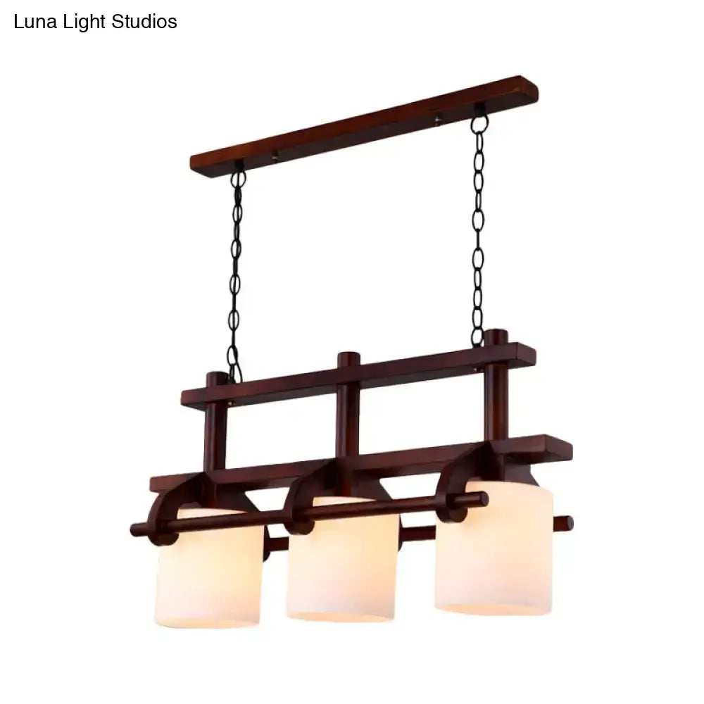 Dark wood-framed pendant island light with three white glass shades suspended by black chains for dining room use