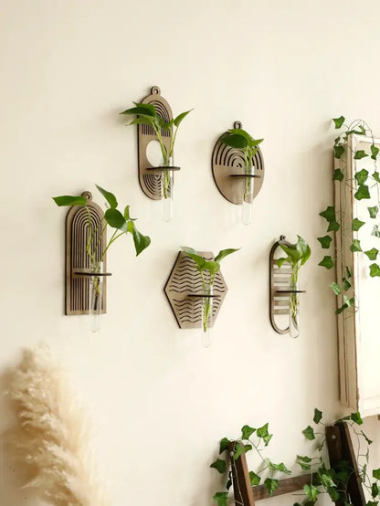Set of five geometric rustic wood wall vases with engraved patterns and glass tubes holding green plants for wall decor