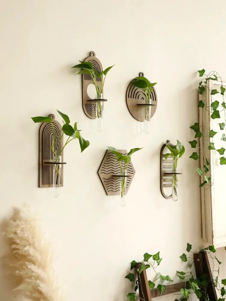 Set of five geometric rustic wood wall vases with engraved patterns and glass tubes holding green plants for wall decor