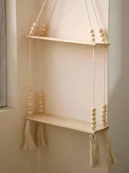 A rustic wooden wall shelf by DecorBites with natural wood finish, beige rope suspension, and decorative tassels