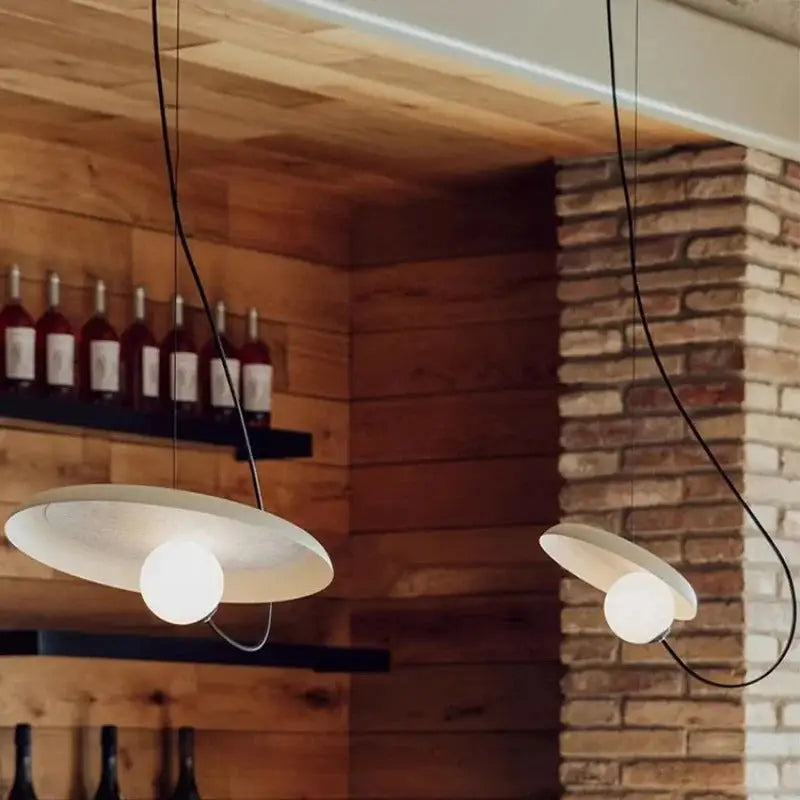 Modern white scandinavian pendant light with sleek minimalist design and black cords hanging from wooden ceiling