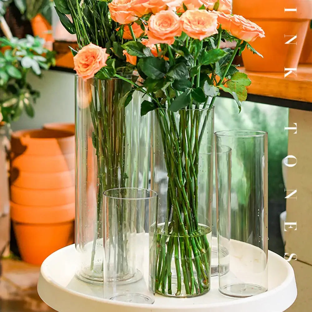 Decorbites™ shatterproof clear acrylic cylinder vases holding peach-colored roses with green leaves in varying heights
