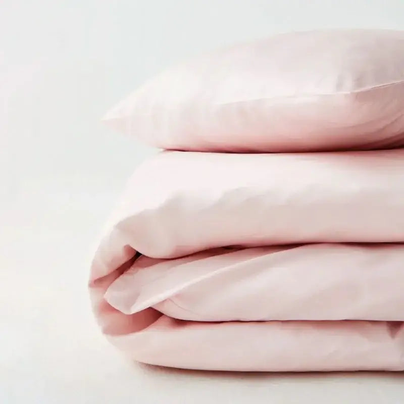 A soft blush-pink satin pillowcase atop a matching duvet cover in the DecorBites silky cooling duvet cover set
