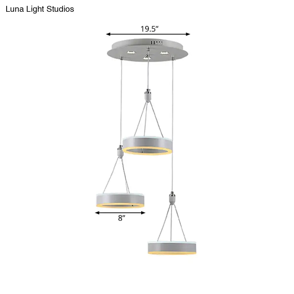 Modern white and silver cluster ceiling light with three tiered metallic rings and warm yellow led glow for dining room