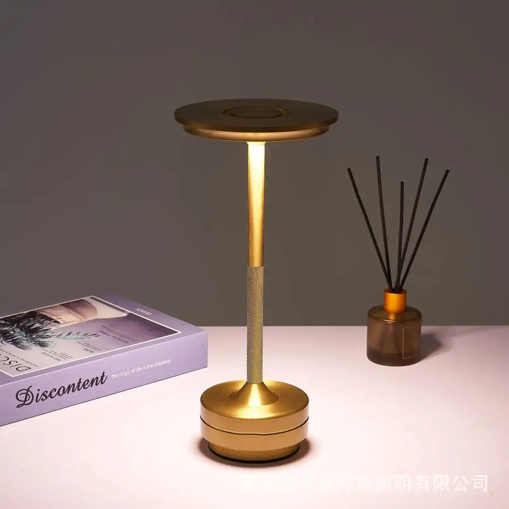 Gold-colored minimalist decorbites™ simple charging led desk lamp with cylindrical base and textured grip section