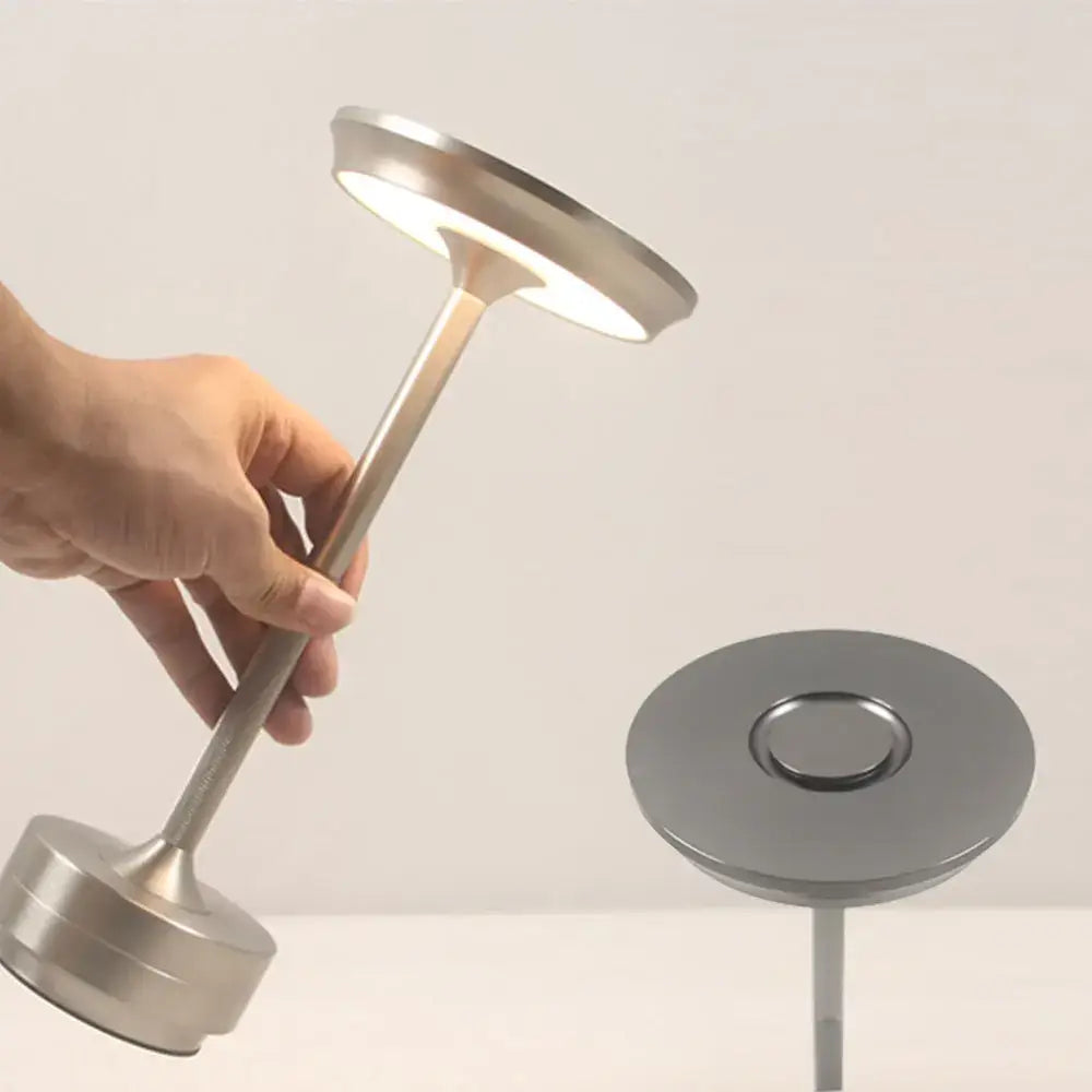 A sleek silver-toned DecorBites simple charging LED desk lamp with minimalist cylindrical stem for office or bar use