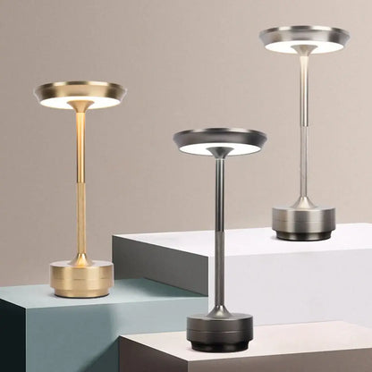Three modern metallic DecorBites™ simple charging led desk lamps in gold silver and black on tiered pedestals