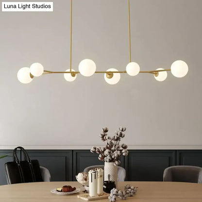 Modern brass pendant light with opal glass globe bulbs in a linear molecular island ceiling design for dining rooms