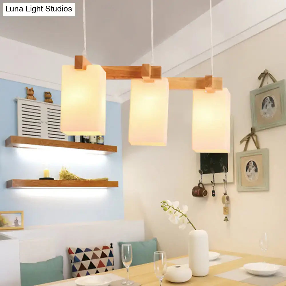 Modern wooden pendant light with three warm-toned opaline glass shades and adjustable chain cord length for island use