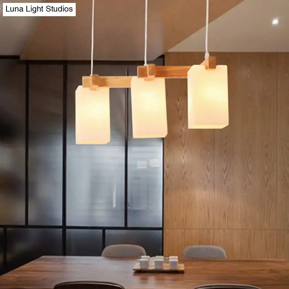 Modern minimalist pendant light with three rectangular opaline glass shades and adjustable chain cord length on wooden crossbar