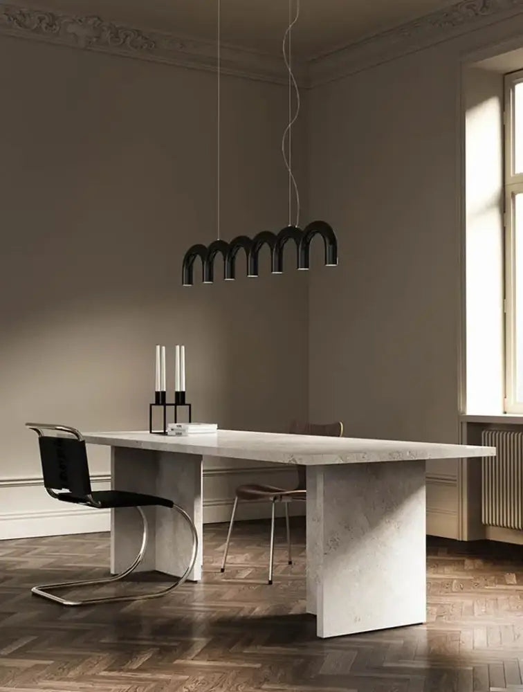 Black arched u-shaped chandelier by DecorBites modern u-shaped chandelier hanging above minimalist dining table