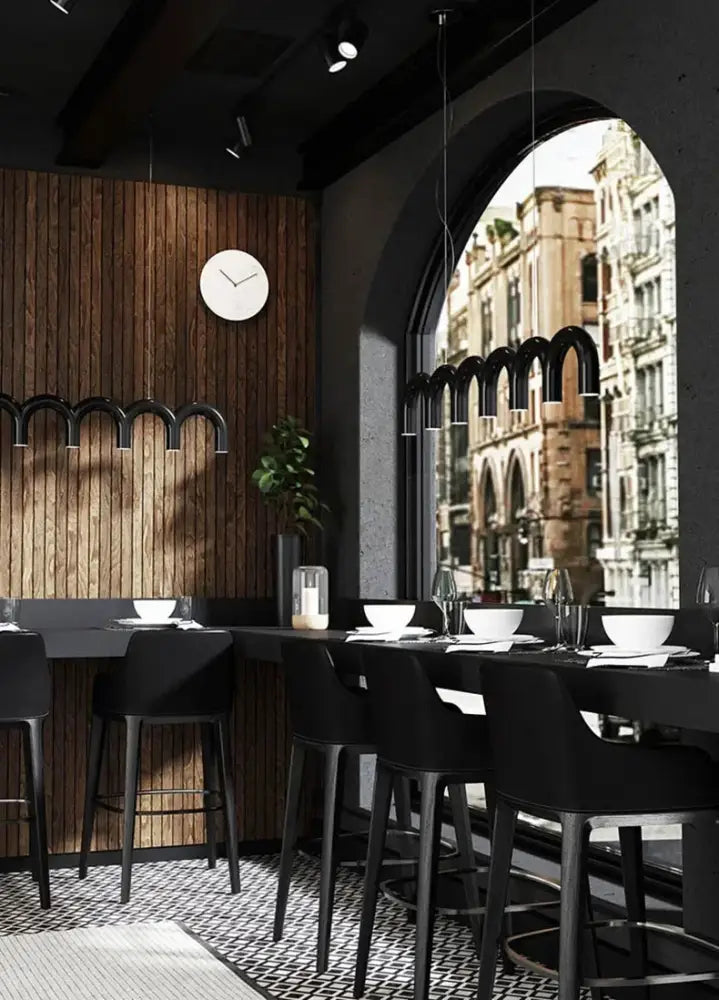 Black bar stools with sleek modern design and minimalist legs complementing a decorbites™ modern u-shaped chandelier