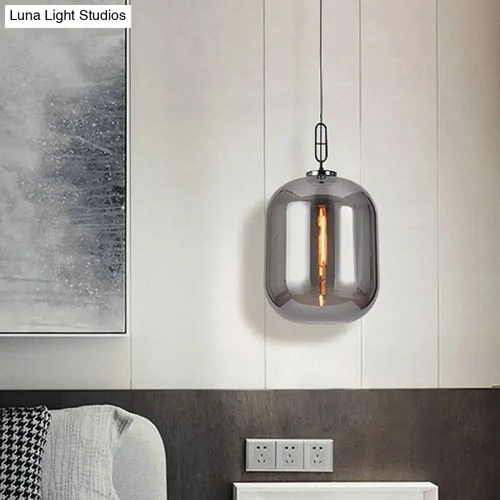 A decorbites smoke gray and cognac glass pendant lamp with a modern cylindrical design and visible filament bulb