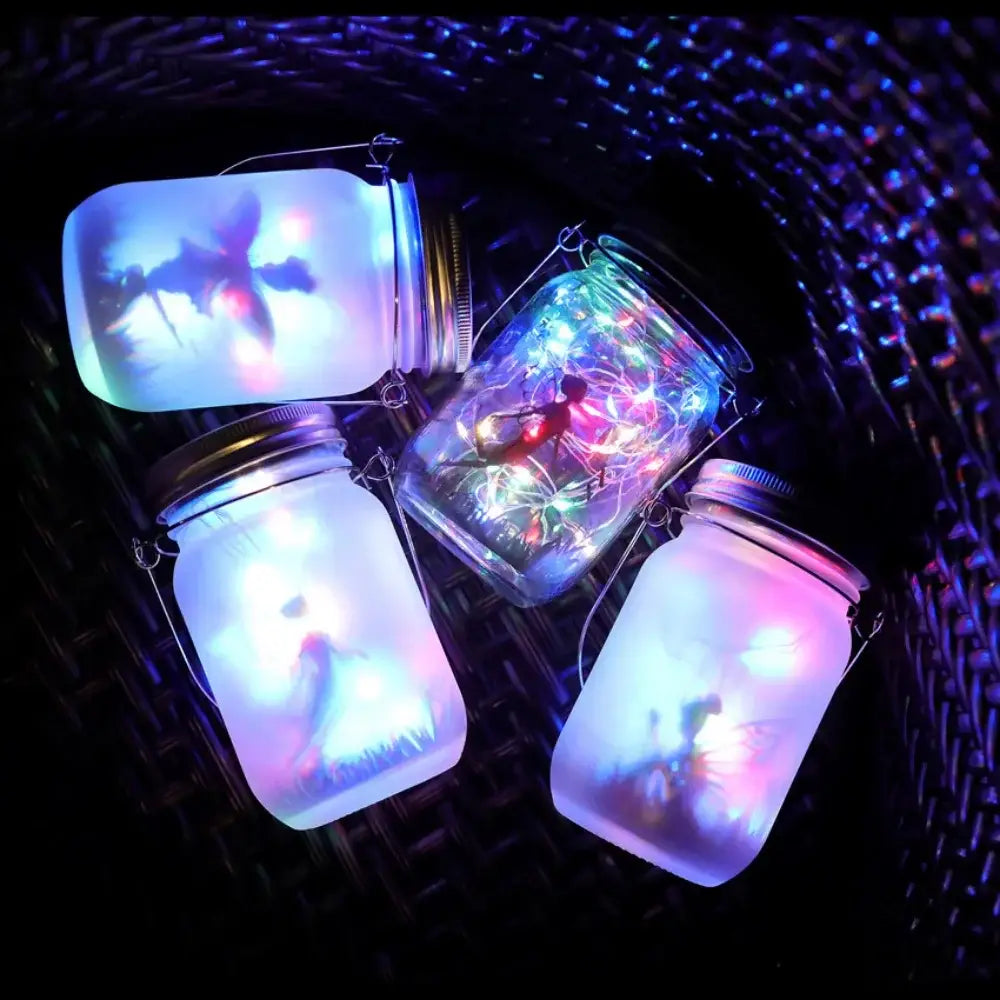 Four illuminated glass solar mason jars with wire handles glowing blue pink and green for garden decoration