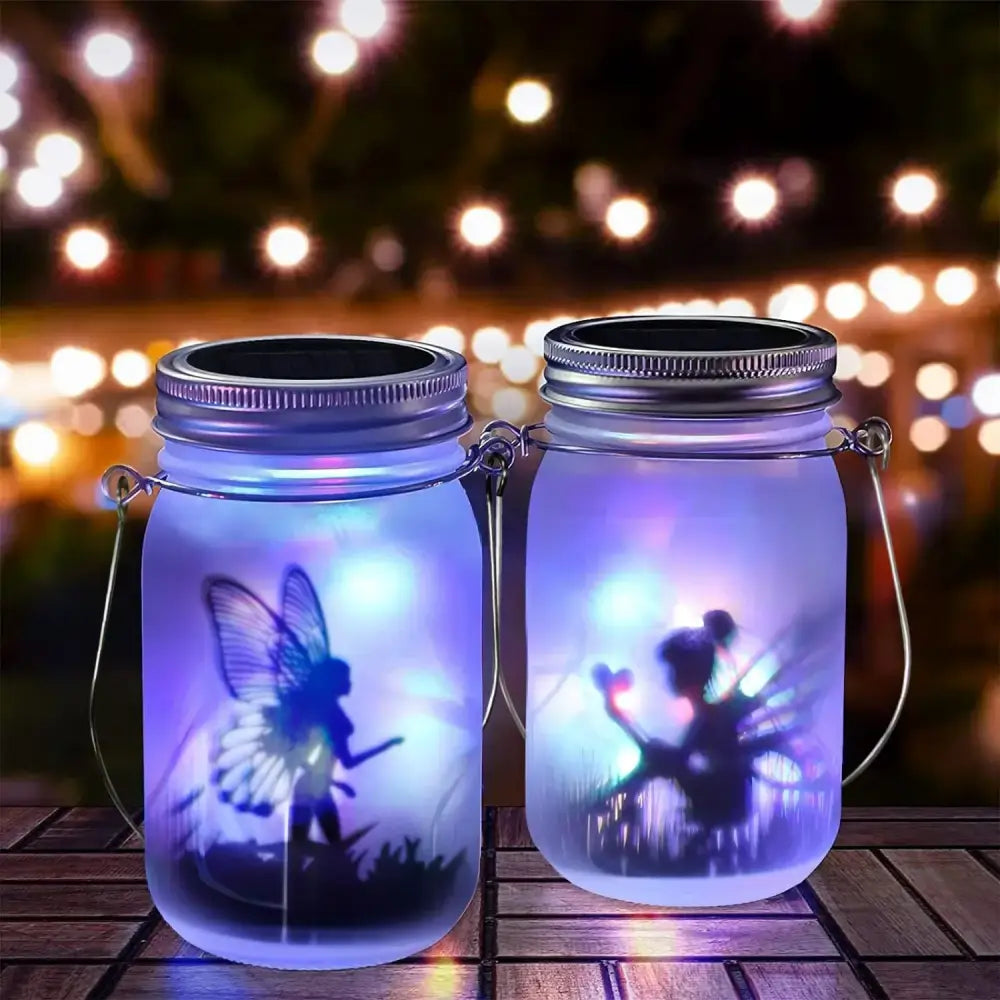 Two illuminated DecorBites™ solar mason jar lanterns with fairy silhouette design glowing soft purple light