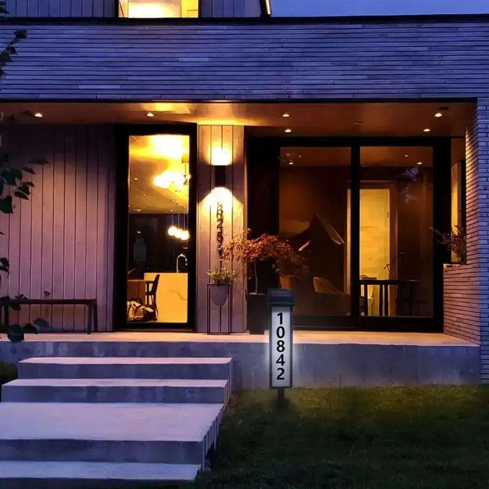 A sleek white solar powered led house number post with illuminated black numerals at a modern home entrance