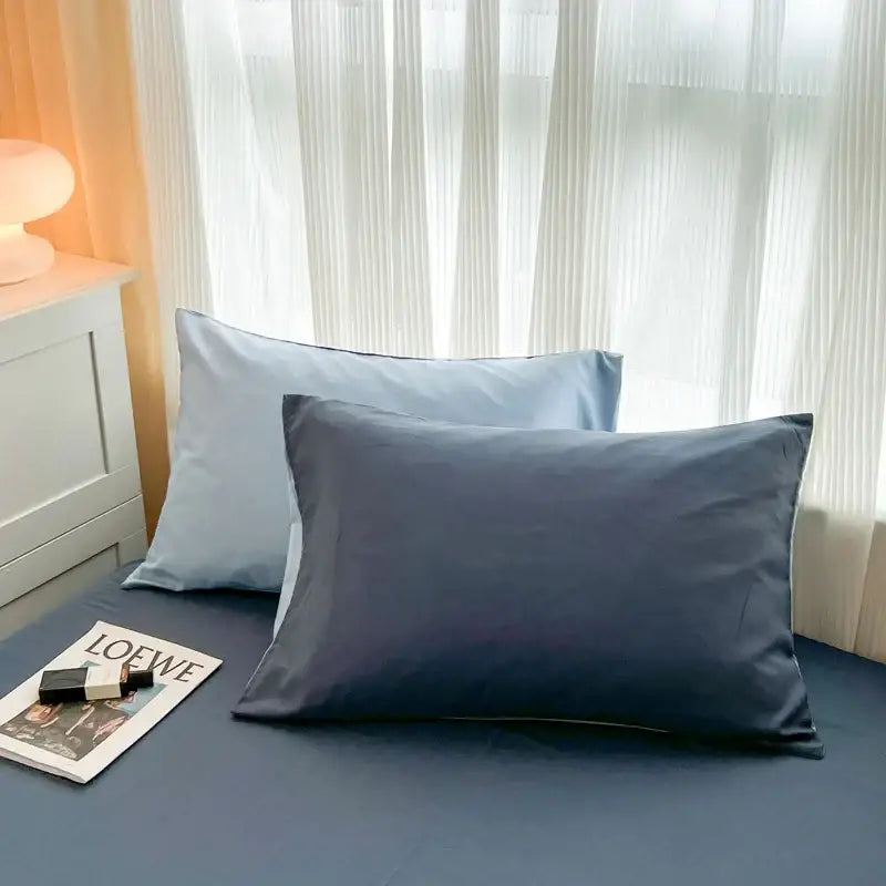 Two rectangular pillowcases in light blue and navy made of smooth satin brush fabric for solid color duvet cover sets