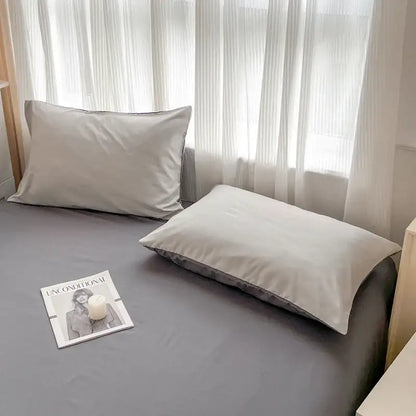 Two beige satin pillowcases with subtle sheen on gray bedsheet from decorbites™ solid color brush fabric bedding set