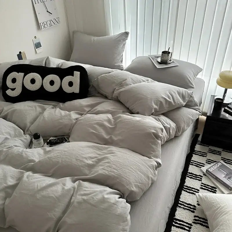 Black knit pillow with white embroidered good lettering complements solid cotton bedding set from decorbites