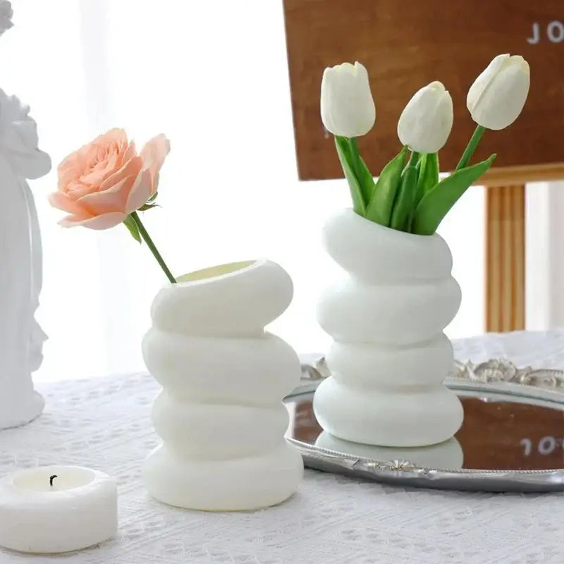 White ceramic spiral white vase with stacked rounded segments holding white tulips for home decor