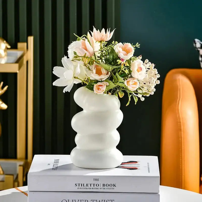 DecorBites™ spiral white vase is a ceramic white vase with a wavy design holding peach and cream artificial flowers
