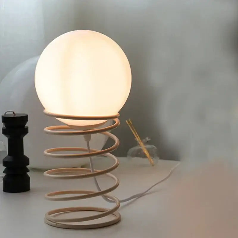 Decorbites™ spring glass table lamp with warm glowing globe and light wood spring base in minimalist bauhaus style