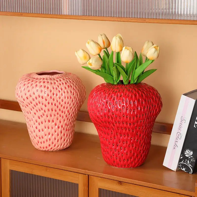 DecorBites™ strawberry cartoon ceramic vase in red with textured surface and green leaves holding yellow tulips for kids room