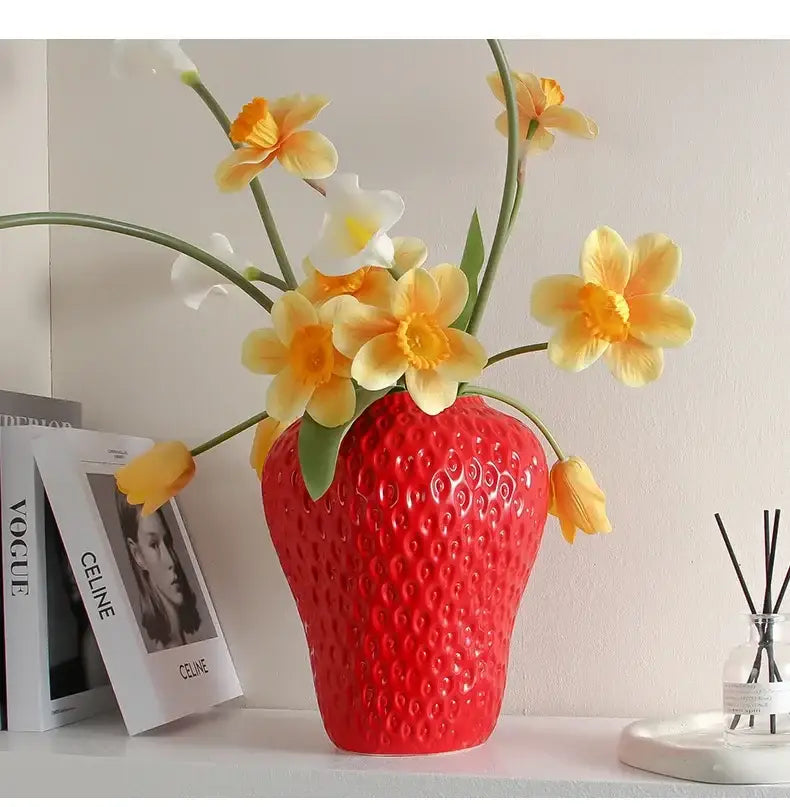 A vibrant red ceramic flower vase shaped like a cartoon strawberry with a textured bumpy surface for home décor