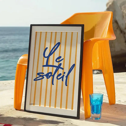 A sleek black framed DecorBites™ summer vibe beach canvas art print with vertical yellow stripes and blue cursive text on cream background