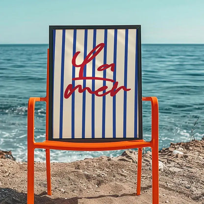 Orange metal chair with framed beach canvas artwork featuring blue white stripes and red script from DecorBites summer vibe posters