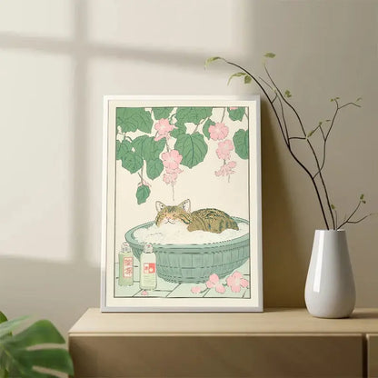 A framed canvas wall art of a tabby cat lounging in a green basin with foam and pink blossoms by DecorBites™