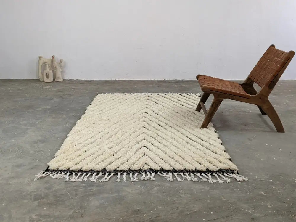 Cream-colored chunky knitted tapis beni ouarain with bold chevron pattern and black border trim by DecorBites™