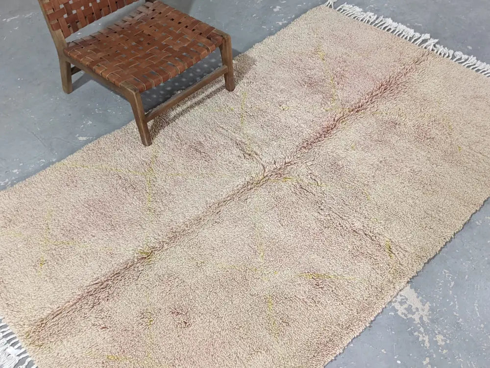 A soft beige and pinkish wool tapis beni ouarain with textured shaggy surface and white fringe edges by decorbites