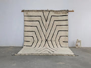 Cream-colored beni ouarain tapis beni with bold black geometric patterns and fringed edges measuring 290 x 213 cm