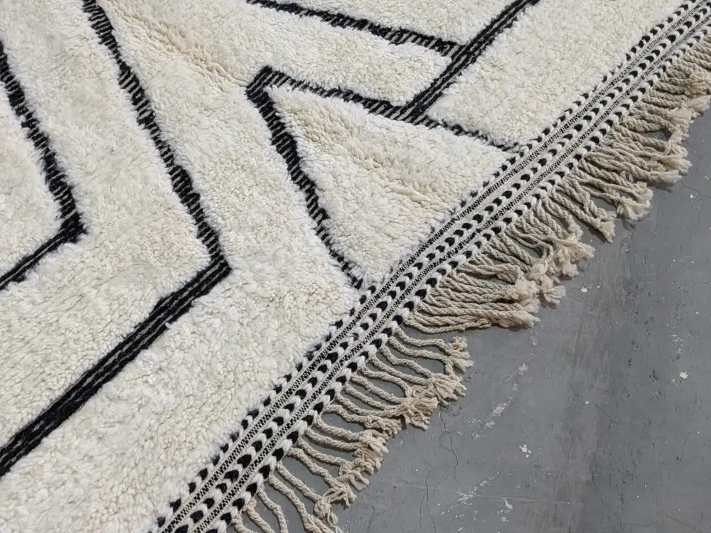 Cream-colored beni ouarain tapis with bold black geometric patterns and fringe border by DecorBites™ 290 x 213 cm