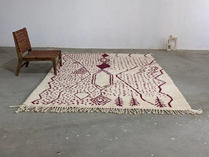 Cream-colored beni ouarain tapis featuring intricate maroon geometric and tree motifs with fringed edges by DecorBites