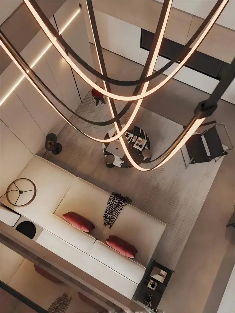 Modern minimalist led chandelier with sleek curved metallic arms and flexible leather belt accents by DecorBites™