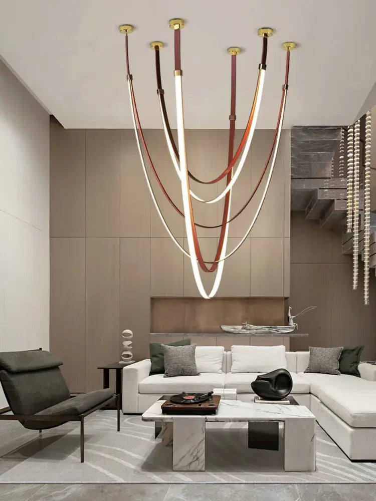 A modern DecorBites™ LED chandelier featuring flexible leather belt strips in white and brown with gold fixtures