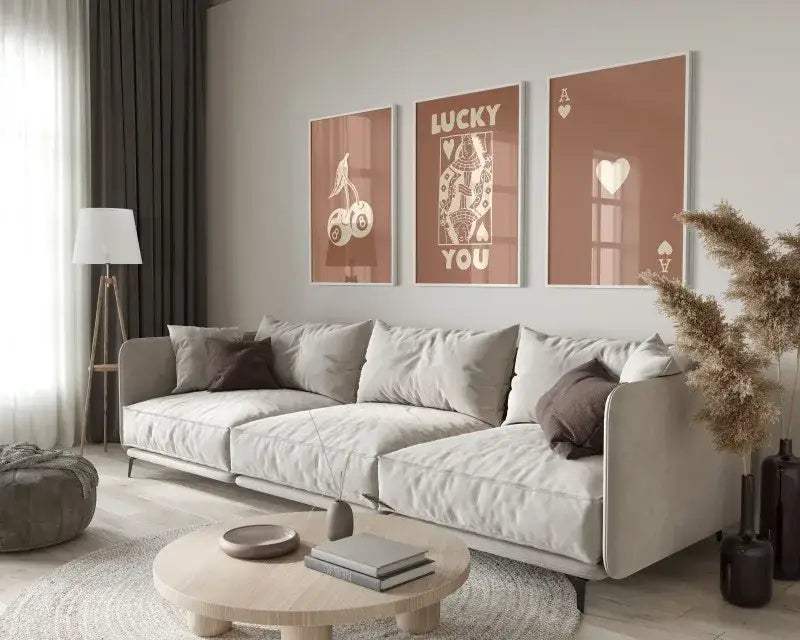 Light gray upholstered sectional sofa with dark brown throw pillows and metal legs next to trendy retro wall art posters