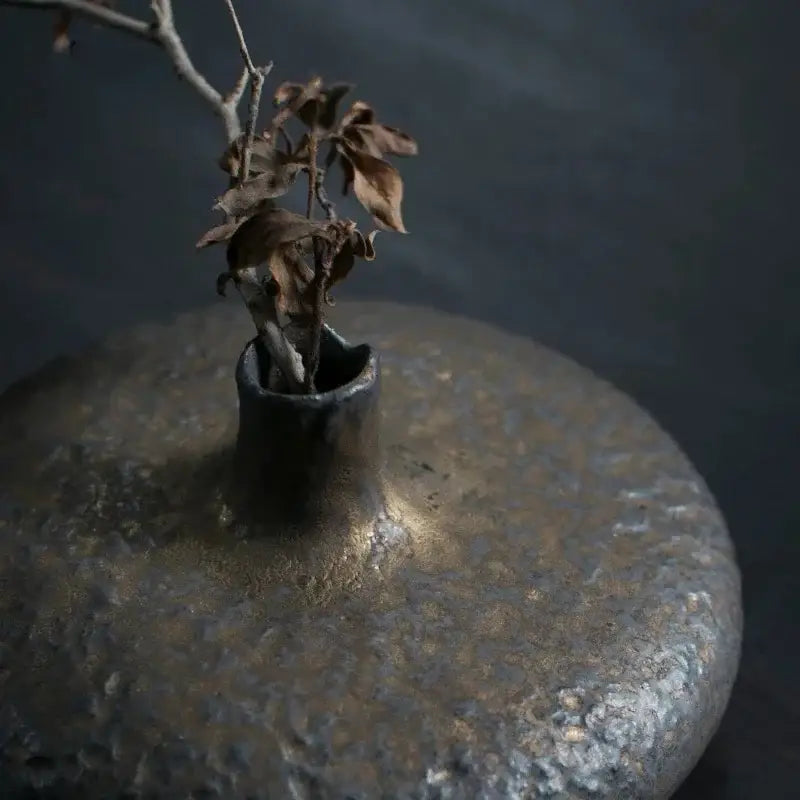 Rustic chinese retro ceramic vase with dark metallic sheen and narrow neck holding dried branches for home decor
